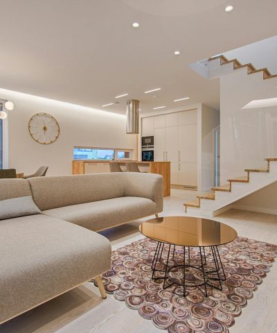 Contemporary living room with neutral tones, a sleek sofa, and elegant wooden staircase.